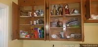 Open kitchen cabinets showing mugs on the left side, Christmas figurines on the middle upper shelf, plastic containers on the middle lower shelves, and metal bowls on the right side.