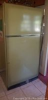 Front view of an avocado green Sears Coldspot refrigerator with two doors.