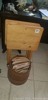 Four stacked rustic pine TV tables with wood bucket containing magazines in front.