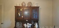 Wide view showing the white glass items, angel figurines, decorative plate, and other items arranged on wood furniture.