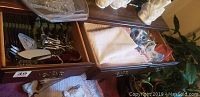Two wooden drawers holding flatware, napkins, napkin rings, and other items