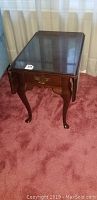 Side angled view of the Bassett end table showing one drop leaf down and the single drawer with brass handle.