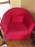 Front view of IKEA armchair with red slipcover and matching pillow showing curved backrest and seat cushion.