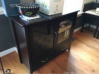 Front and angled view of the dark wood buffet server showing two glass inset doors with silver handles, two drawers below, and items displayed on top.