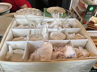 Padded storage container with compartments housing the glassware and china items.