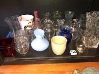 Overview of the collection showing various glass, ceramic and metal vases and pails arranged on a shelf, highlighting variety and approximate count.