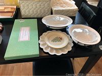 Photo showing green box with fish platter inside, two covered serving bowls on black stands, Lenox plate and egg plate arranged together on black table