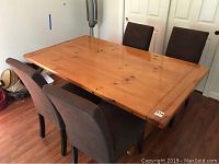 Set of four brown velour upholstered dining chairs around a wooden dining table on wood flooring.