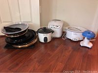Photo of all items on floor showing bread maker, rice cooker, crock pot, snow cone machine, and plastic bowls with serving tongs