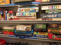 Shelf of assorted board games showing titles including Mouse Trap, The Game of LIFE, Zathura, Clue, Go To The Head of the Class.