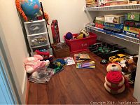 Wide view of toys, games, plush toys, and toy cars on table and shelves.