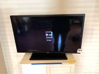 Front view of the 32-inch LG flat screen TV powered on, displaying LG logo and 'No Signal' message. Mounted on a stand.