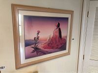 Framed RC Gorman print showing Native American woman with flower, purple background, wooden frame.