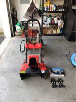 Photo of the Maztang electric snow thrower with two slip-on crampons and a blue box for car traction mats