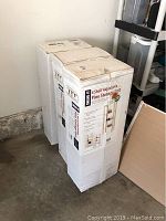 Two unopened boxes of 4 shelf adjustable pine storage units stacked in garage corner.