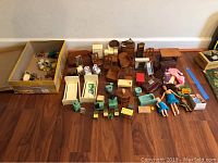 Full view showing assortment of vintage metal, plastic, and wooden dollhouse furniture pieces and four dolls including a Mego Charlie's Angels doll
