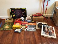 Photo of various vintage toys and collectibles including Pac Man tray, games, books, mug, Roy Rogers bootsters and photo print