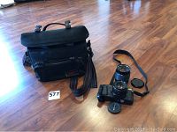 Photo of the Pentax camera bag, camera with lenses and accessories laid out on wood floor.