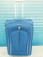 Front view of blue softside rolling suitcase with telescopic handle extended, two front zippered compartments, and Atlantic logo near top.