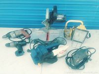 Full view of all items in lot showing Delta compound miter saw, two drills, two sanders, and work light.