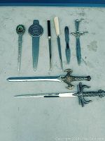 All seven vintage letter openers laid out flat to show variety and general condition.