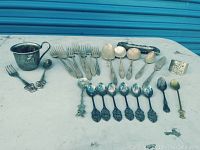 Full collection of flatware and the kids cup laid out on a table, showing the variety and quantity of items including forks, spoons, cup, and a napkin ring.
