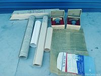 View of multiple rolled parchment replicas, Liberty Bell replicas in boxes, and authentication envelope.