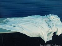 Full view of the wedding dress laid out flat showing the long train with lace and bead details.