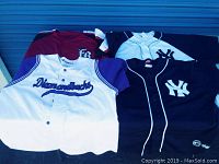 Four baseball shirts laid flat, two Diamondbacks and two Yankees shirts with visible logos and colors.
