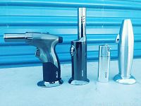 Photo showing all 4 Zico refillable butane lighters arranged in a row on a blue surface with blue corrugated background.