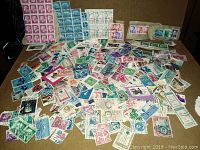 Wide shot of numerous loose vintage stamps spread out showing variety in color and design