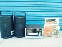Wide view of all items: 8 track player, two Bluetooth speakers, Robons tape eraser box, and vinyl record cleaner box.