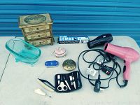 Overview of assorted ladies vanity items on table including jewelry box, compacts, hair dryers, grooming kit, combs and nail file