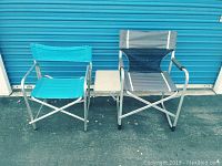 Two collapsible chairs side by side against a blue door. One turquoise, one gray with black mesh and white piping.