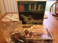 Photo showing original boxes for AMT Interplanetary U.F.O. Mystery Ship and 1/40 scale Military Series G.I. Soldiers model kits with some model parts in plastic bags