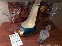 Overall lot showing shoe bottle holder, two cocktail glasses, crystal bottle stopper, and Carolyn Oltman canvas prints in background.