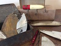 Metal box with seven aged metal spoon lures and one large wooden red and white fishing lure