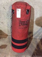 Close-up of red Everlast punching bag showing chain, metal hooks, and logo with visible dirt and wear.