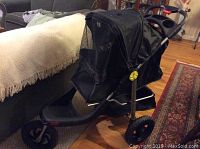 Photo of black jogging stroller from front angle showing mesh tent covering and three large wheels