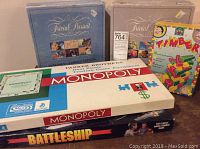 Lot of 5 vintage games including Monopoly, Trivial Pursuit, Battleship and Timber games stacked for display.