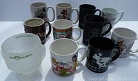 Image showing all 12 mugs arranged together on a white surface, capturing the variety of styles and themes including black mugs with character silhouettes, and colorful character mugs.
