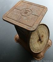 Side and angled view of the rusty metal square top platform and base of the scale with visible rust and corrosion.