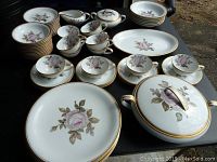 Photo of full set arranged showing multiple pieces including plates, cups, saucers, creamer, sugar bowl with lid, and covered serving bowl