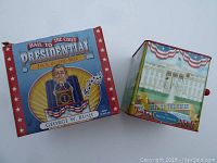 Front and side view of the original box and the jack-in-the-box featuring a George W. Bush figure and White House artwork.