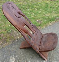 Angled front view of assembled chair showing elephant carving, seat and X-shaped base