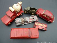 Overview of entire lot showing all six vintage toy vehicles on a black background