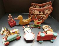 Photo showing a group of vintage hand-painted wooden pull toys including a yellow duck, red chicken, ladybug music box, horse, dog pull toy, and small figure on red base.
