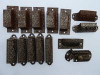 Vintage metal door and drawer hardware with embossed floral and geometric designs.