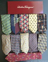 Top view of ten designer neckties laid flat, includes pairs in a Salvatore Ferragamo box and various patterns from Burberry, Gucci, and others.