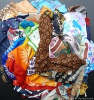 Top view of a large collection of colorful scarves, handkerchiefs, and ties showing various patterns including polka dots, florals, and geometric designs.